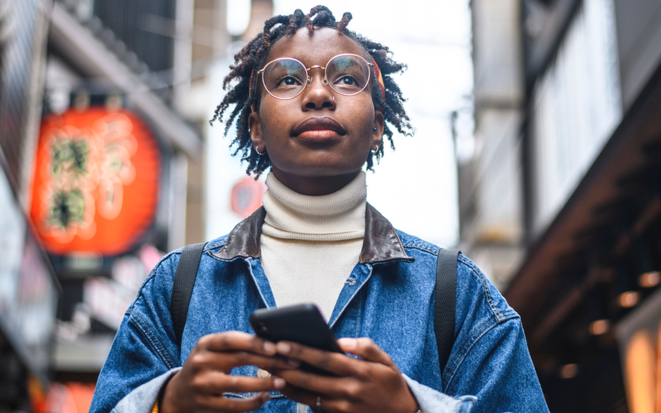 person holding a smartphone and walking in a city street